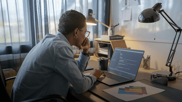 Person-critically-thinking-and-resizing-an-image-using-code-on-a-laptop-in-an-office